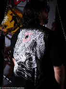 Person wearing a black t-shirt with a white graphic design on the back, standing in a dark room.